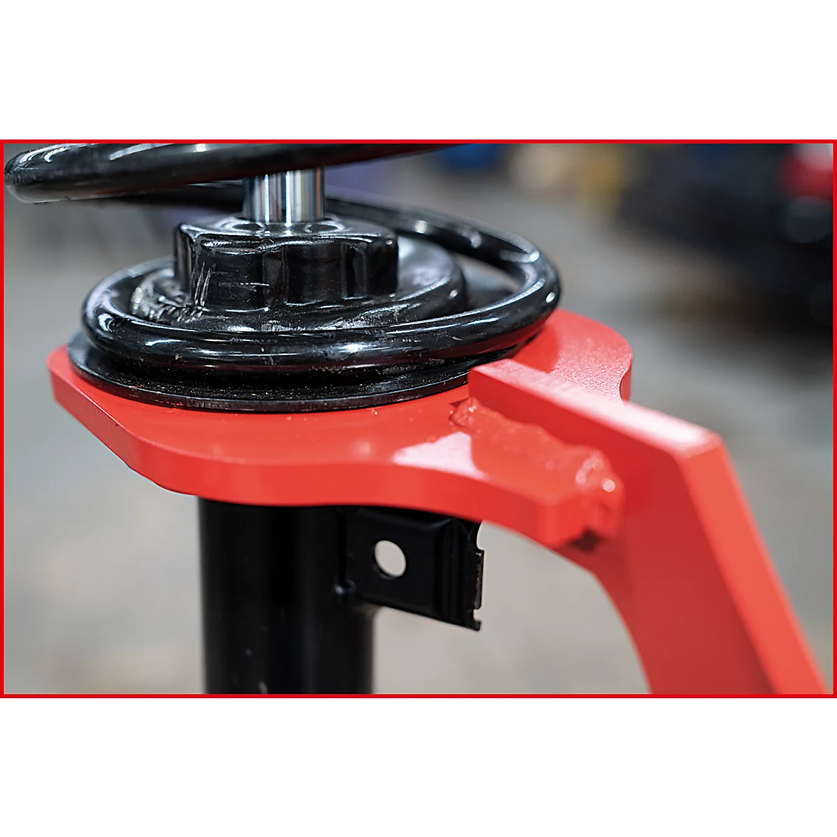 Nahaufnahme eines Teils einer Hebebühne: schwarze Feder, roter Arm, schwarzer Sockel.